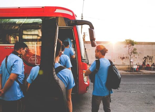 Group of tourists boarding a red charter bus at sunset